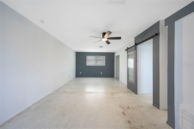 spare room featuring a barn door and ceiling fan