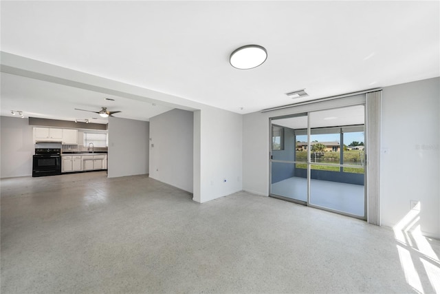 unfurnished living room featuring ceiling fan and sink