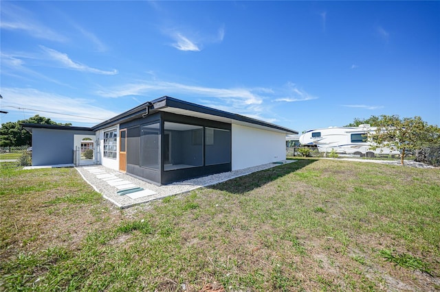 back of house featuring a lawn and a sunroom