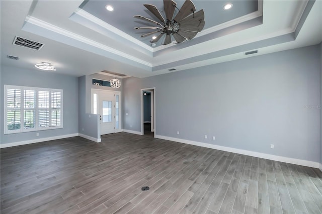 spare room with a tray ceiling, crown molding, and hardwood / wood-style flooring