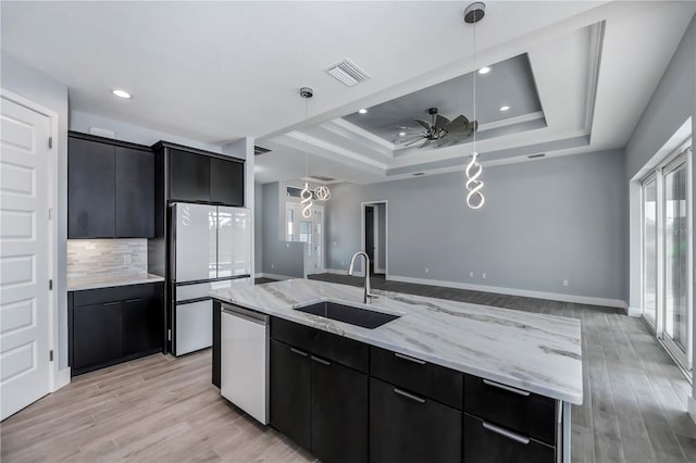 kitchen with appliances with stainless steel finishes, a spacious island, sink, light hardwood / wood-style flooring, and hanging light fixtures