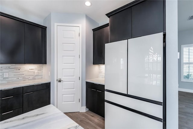 kitchen with backsplash, light stone counters, and light hardwood / wood-style flooring