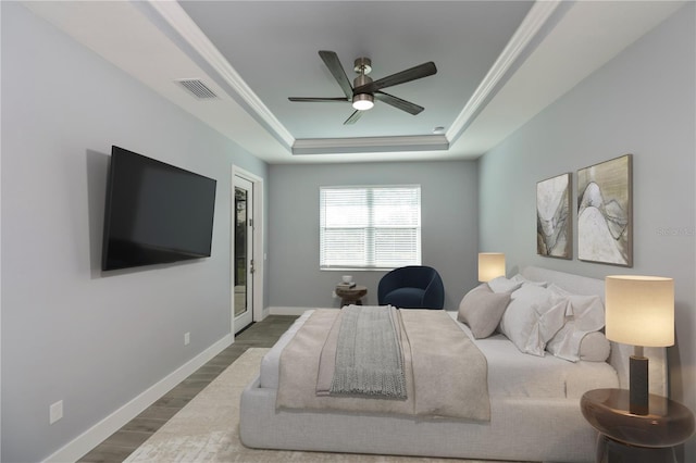 bedroom featuring hardwood / wood-style flooring, ceiling fan, a raised ceiling, and ornamental molding