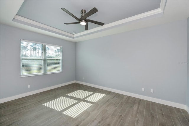 empty room featuring a tray ceiling, ceiling fan, and wood-type flooring