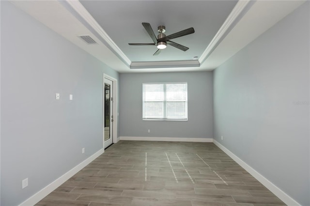 spare room featuring a tray ceiling, ceiling fan, light hardwood / wood-style floors, and ornamental molding