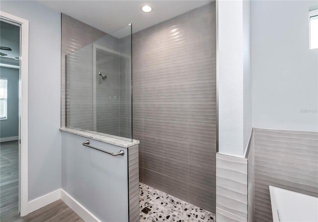 bathroom with tiled shower and hardwood / wood-style flooring