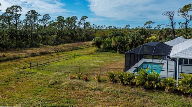 view of yard featuring a fenced in pool, glass enclosure, and a rural view