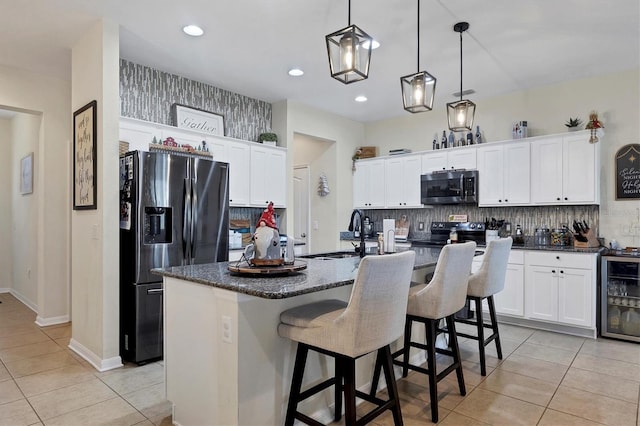 kitchen featuring white cabinetry, sink, stainless steel appliances, wine cooler, and an island with sink