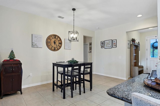 dining space with light tile patterned floors and an inviting chandelier