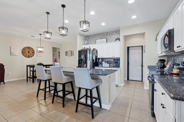 kitchen featuring a kitchen breakfast bar, a kitchen island with sink, white cabinets, black appliances, and light tile patterned flooring