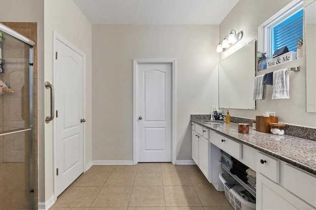 bathroom featuring vanity, baseboards, tile patterned floors, and a shower stall