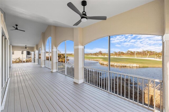 wooden deck with ceiling fan and a water view