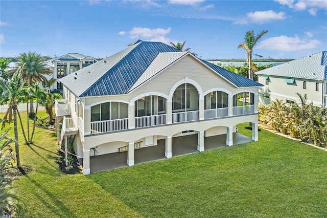 rear view of property featuring a sunroom and a lawn