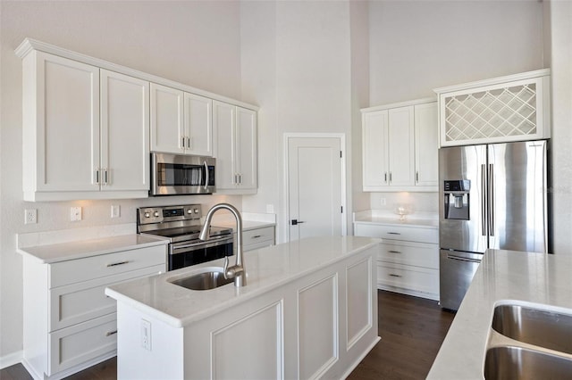 kitchen with white cabinets, an island with sink, stainless steel appliances, and dark hardwood / wood-style floors