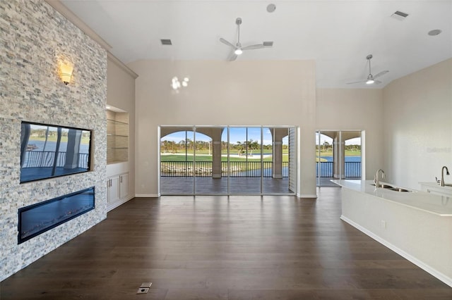 unfurnished living room with a healthy amount of sunlight, dark hardwood / wood-style flooring, and a stone fireplace