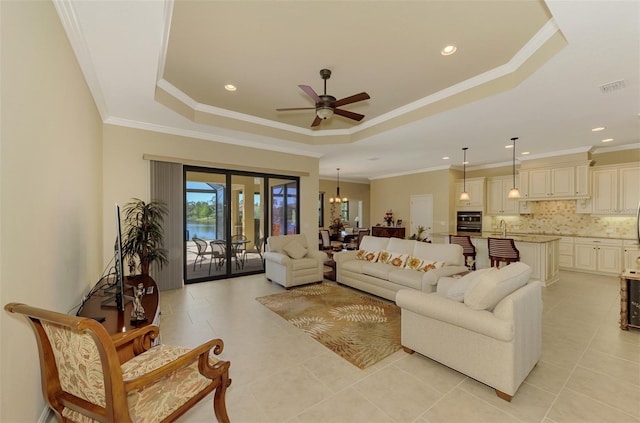 tiled living room with a raised ceiling, ceiling fan with notable chandelier, and ornamental molding