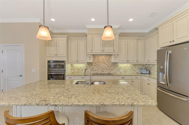 kitchen featuring pendant lighting, a kitchen bar, stainless steel appliances, and cream cabinets