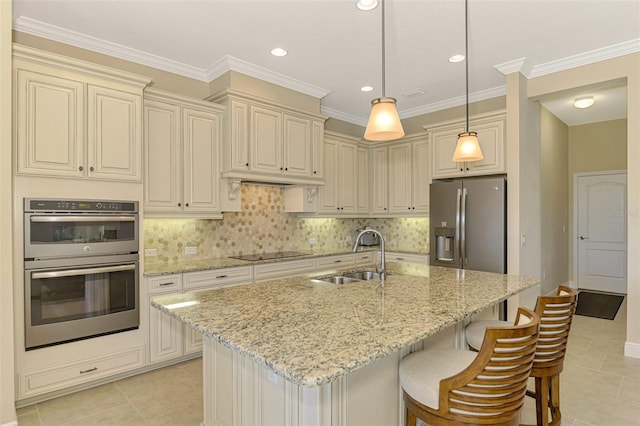 kitchen featuring light stone countertops, stainless steel appliances, sink, pendant lighting, and cream cabinets