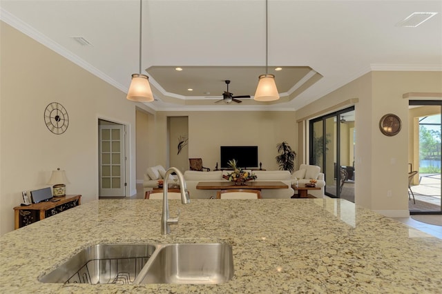 kitchen with crown molding, sink, hanging light fixtures, ceiling fan, and light stone counters