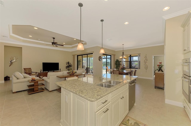 kitchen with light stone countertops, ceiling fan with notable chandelier, sink, decorative light fixtures, and an island with sink