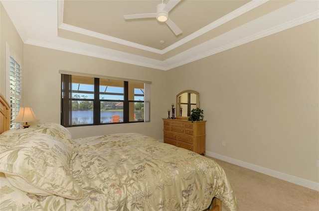 carpeted bedroom featuring a tray ceiling, ceiling fan, crown molding, and a water view