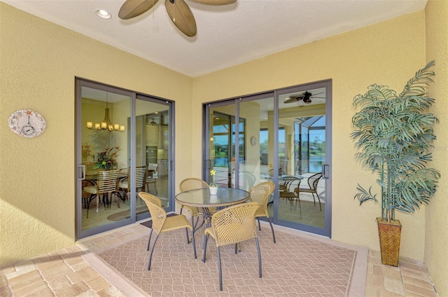 sunroom featuring ceiling fan with notable chandelier