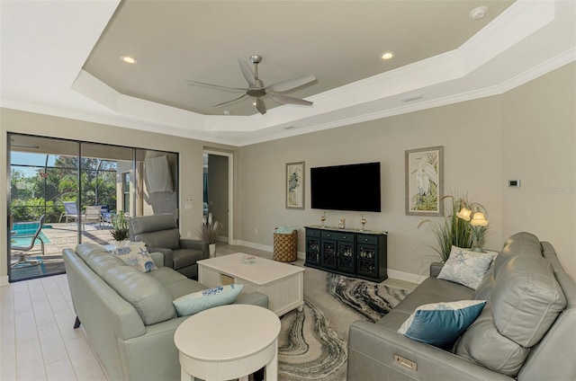 living room with ceiling fan, a raised ceiling, and ornamental molding