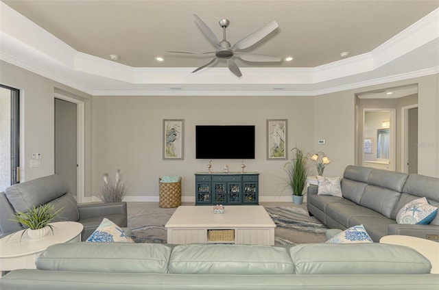 living room with a tray ceiling, ceiling fan, and crown molding