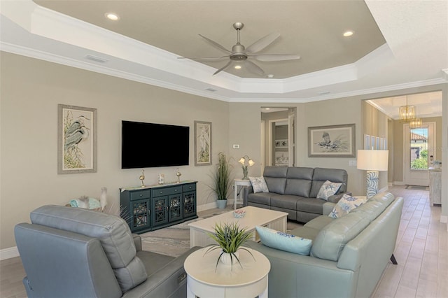 living room with a tray ceiling, crown molding, and light hardwood / wood-style floors