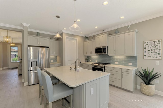 kitchen featuring appliances with stainless steel finishes, backsplash, crown molding, a center island with sink, and hanging light fixtures