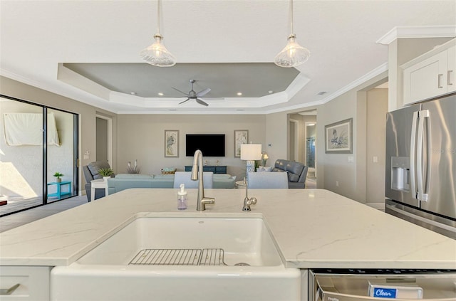 kitchen with a raised ceiling, pendant lighting, stainless steel appliances, and sink