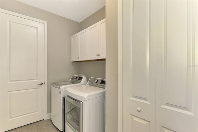 laundry room featuring washer and dryer, light hardwood / wood-style floors, and cabinets