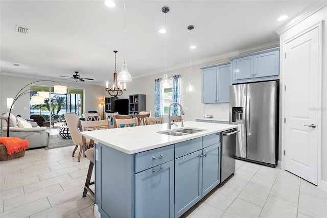 kitchen featuring sink, blue cabinetry, appliances with stainless steel finishes, hanging light fixtures, and a center island with sink