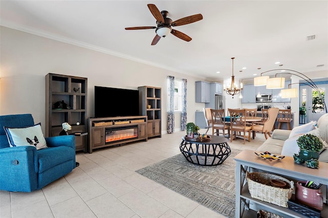 living room with light tile patterned floors, ceiling fan with notable chandelier, and ornamental molding