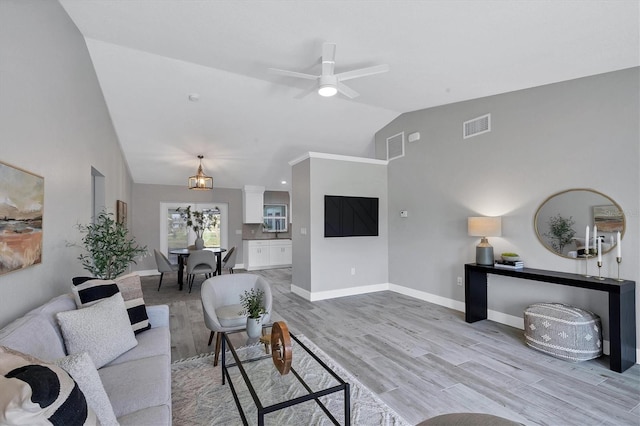 living room featuring ceiling fan, light hardwood / wood-style floors, and vaulted ceiling