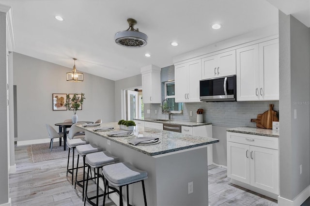 kitchen with a kitchen island, white cabinetry, appliances with stainless steel finishes, and light hardwood / wood-style flooring