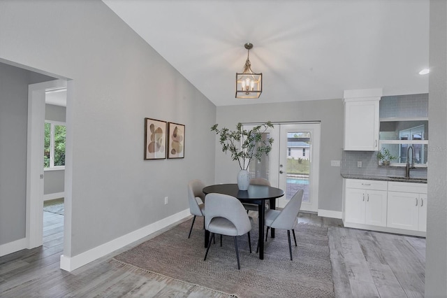 dining area featuring a chandelier, light hardwood / wood-style floors, sink, and french doors