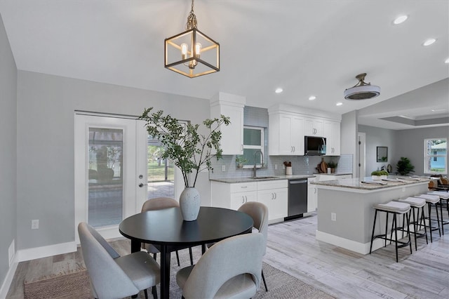 dining area featuring a chandelier, french doors, light wood-type flooring, and sink