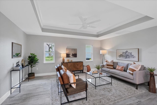 living room with light wood-type flooring, a tray ceiling, and a wealth of natural light