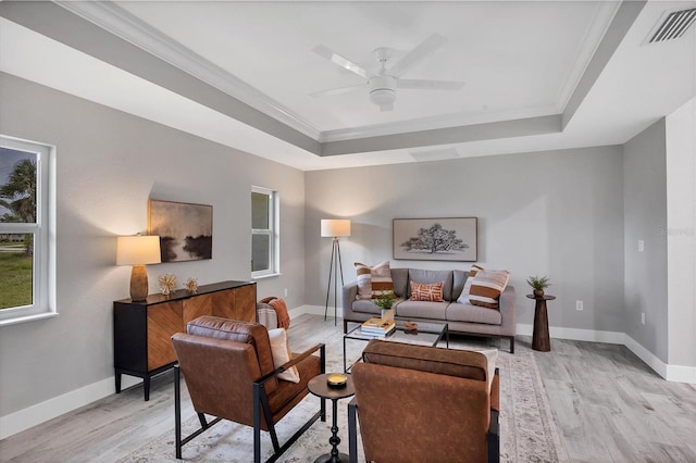 living room with a tray ceiling, crown molding, and light hardwood / wood-style flooring