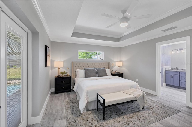 bedroom featuring ceiling fan, crown molding, light wood-type flooring, and ensuite bathroom