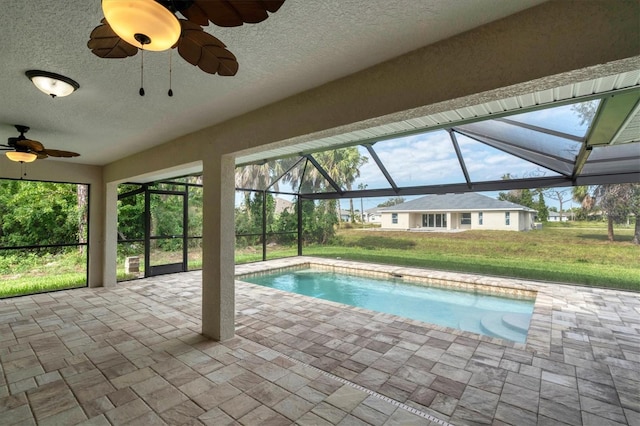 view of swimming pool featuring a lanai, ceiling fan, a patio area, and a lawn