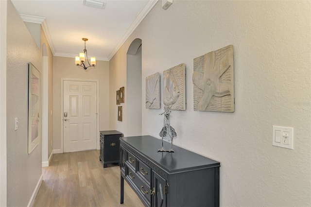 hall featuring hardwood / wood-style flooring, an inviting chandelier, and ornamental molding