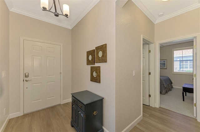 entrance foyer featuring an inviting chandelier, ornamental molding, and light wood-type flooring