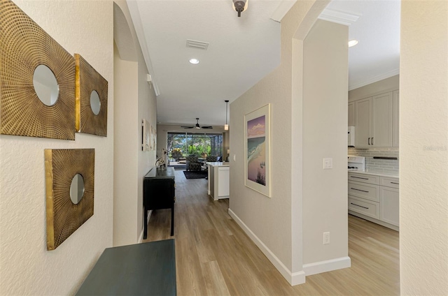 corridor with crown molding and light wood-type flooring