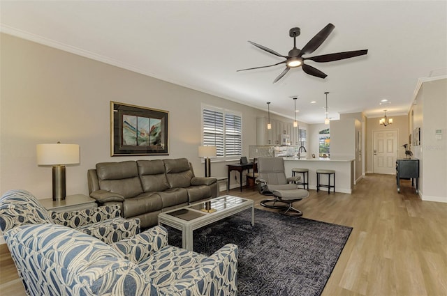 living room featuring sink, light hardwood / wood-style floors, ceiling fan with notable chandelier, and ornamental molding