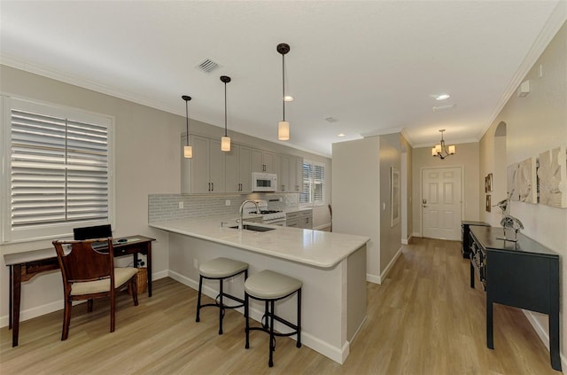 kitchen with light hardwood / wood-style flooring, ornamental molding, stainless steel range, a notable chandelier, and kitchen peninsula