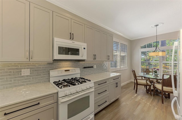 kitchen with light stone countertops, white appliances, crown molding, light hardwood / wood-style flooring, and hanging light fixtures