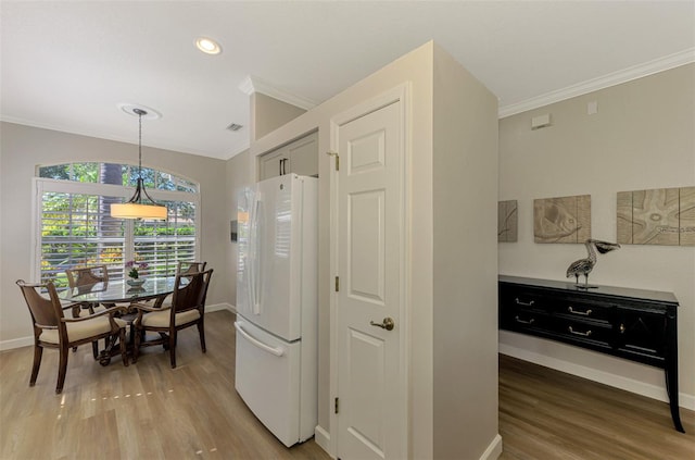 kitchen featuring hardwood / wood-style floors, white fridge, hanging light fixtures, and ornamental molding