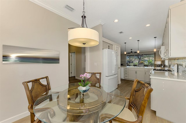 dining area featuring light hardwood / wood-style flooring and crown molding